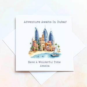 May include: A white greeting card featuring a Dubai skyline illustration with the Burj Al Arab. The card says "Adventure Awaits In Dubai!" and "Have A Wonderful Time Amelia". A sailboat is depicted on the water, with palm trees.