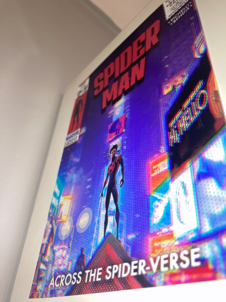 Puede incluir: Una portada de c&oacute;mic con Spider-Man de pie en un edificio en un horizonte urbano. La portada es de un azul vibrante con acentos rojos y amarillos. El texto en la portada dice "Spider-Man" y "Across the Spider-Verse".