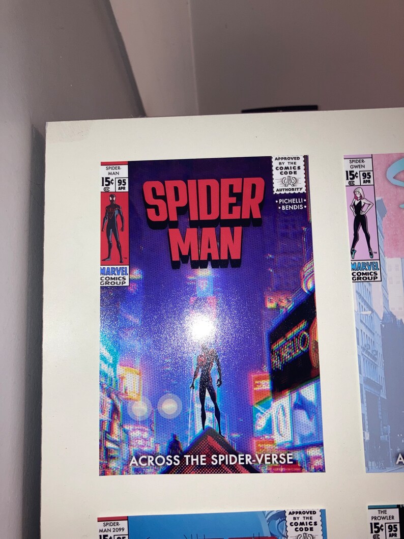 Puede incluir: Una portada de c&oacute;mic con Spider-Man de pie en un edificio en un horizonte urbano. La portada es azul y morada con un efecto glitch. El texto en la portada dice "Spider-Man" y "Across the Spider-Verse".