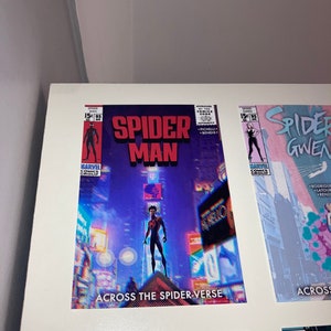 Puede incluir: Una portada de c&oacute;mic con Spider-Man en un traje negro y rojo de pie en un edificio en un horizonte urbano. La portada se titula "Spider-Man: Across the Spider-Verse".