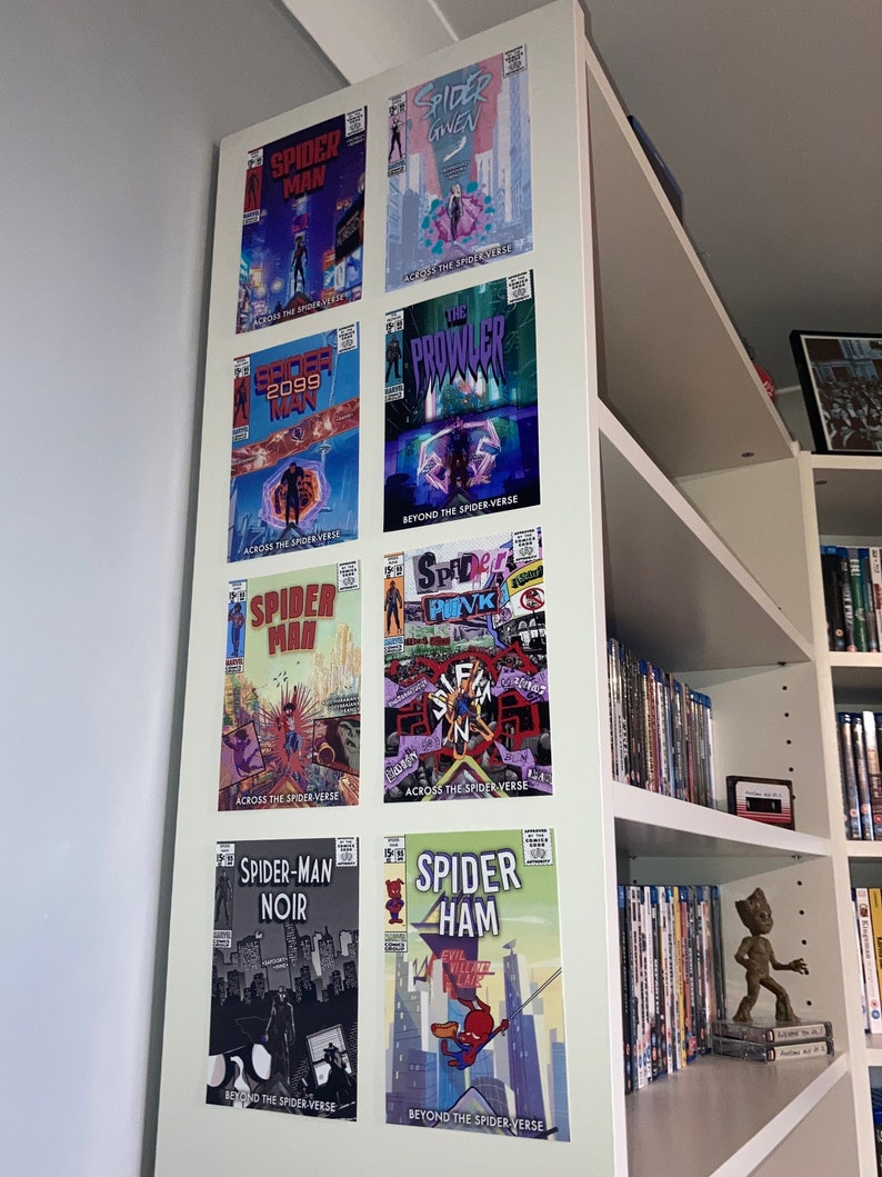 Puede incluir: Una estanter&iacute;a blanca con ocho portadas de c&oacute;mics que presentan diferentes personajes de Spider-Man. Las portadas est&aacute;n dispuestas en dos filas de cuatro. Las portadas son todas de las pel&iacute;culas "Spider-Man: Across the Spider-Verse" y "Spider-Man: Beyond the Spider-Verse". Las portadas presentan a Spider-Man, Spider-Gwen, Spider-Man 2099, Spider-Punk, Spider-Man Noir y Spider-Ham.