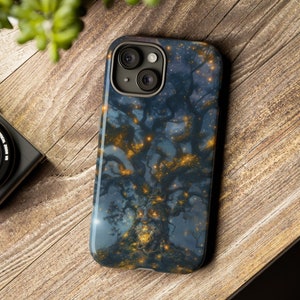 Puede incluir: Una funda para teléfono con un fondo azul oscuro que presenta un árbol estilizado con luces brillantes. El árbol está rodeado de un cielo estrellado. La funda tiene un recorte para la cámara del teléfono.