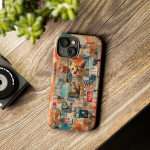 May include: A phone case with a collage design and a ginger kitten. The case has a vintage aesthetic with newspaper clippings and colourful accents. The phone case is on a wooden surface.