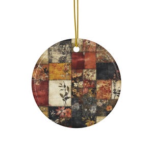 Puede incluir: Un adorno redondo de cerámica con un diseño de patchwork en varios tonos de marrón, rojo y amarillo. El diseño de patchwork incluye patrones florales e ilustraciones botánicas.