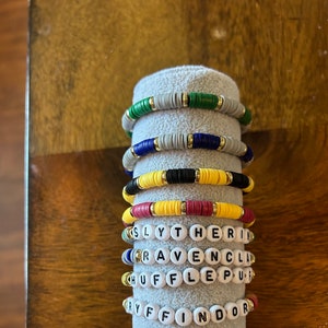 May include: Four colorful beaded bracelets with the names of the Hogwarts houses: Slytherin, Ravenclaw, Hufflepuff, and Gryffindor.