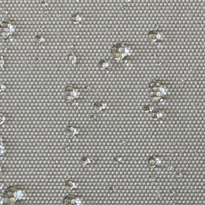 May include: Close-up of a grey, textured fabric with small, white water droplets scattered across the surface.