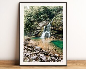 Könnte beinhalten: Ein gerahmtes Foto eines Wasserfalls, der eine felsige Klippe hinunter in einen türkisfarbenen Pool stürzt. Üppige grüne Bäume umgeben den Wasserfall und schaffen eine ruhige und natürliche Szene.