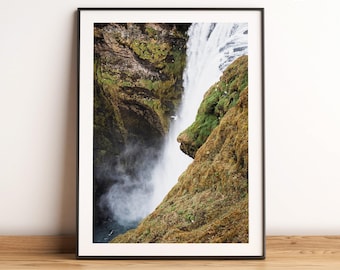 May include: A close-up view of a waterfall cascading down a moss-covered cliff. The water is white and foamy, and the cliff is a mix of green and brown.