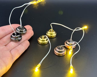 Puede incluir: Cinco pequeñas luces LED a pilas con cables transparentes y bases de metal. Las bases son de tres colores diferentes: dorado, plateado y cobre.
