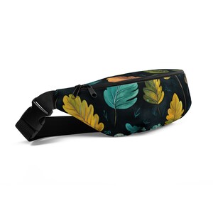 May include: A black fanny pack with a zipper closure and adjustable strap. The pack features a repeating pattern of colourful leaves on a dark background.