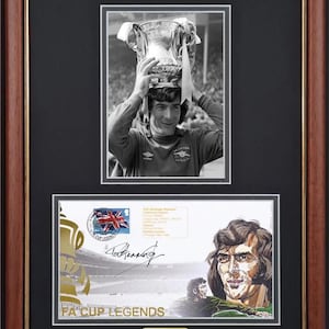Puede incluir: Marco de madera marrón con borde dorado que contiene una foto en blanco y negro de un futbolista sosteniendo un trofeo, encima de una conmemoración firmada de las Leyendas de la FA Cup. Una etiqueta de edición limitada con el número 125 está en la parte inferior.
