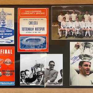 May include: A framed collage of photos and tickets from the 1967 FA Cup Final between Chelsea and Tottenham Hotspur. The collage includes a photo of the Tottenham Hotspur team holding the trophy, a photo of the team captain holding the trophy, and two tickets for the game.