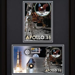 May include: Framed Apollo 11 commemorative art. The artwork features two panels with images of the Apollo 11 mission, including astronauts on the moon, a rocket launch, and a stamp. The text "Apollo 11" is displayed in gold lettering.