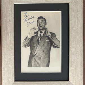 Peut inclure: Photographie encadrée en noir et blanc de Frankie Laine, avec une inscription manuscrite. La photo est dans un cadre en bois argenté avec un passe-partout noir. L'image montre Frankie Laine en costume, gesticulant avec ses mains.