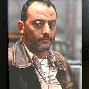 Peut inclure: Photographie encadrée d'un homme aux cheveux courts et foncés et à la barbe, portant une veste en cuir marron sur une chemise rayée. La photographie est signée à l'encre noire. Le cadre est noir.