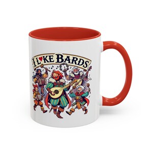 Peut inclure: Une tasse en céramique blanche avec une bordure et une poignée rouges. La tasse présente une illustration colorée d'un groupe de musiciens jouant des instruments avec le texte "I ♥ KE BARDS" sur le devant.