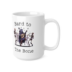 Könnte beinhalten: Eine weiße Keramiktasse mit einer Schwarzweißillustration eines Barden, der eine Laute spielt, während Skelette um ihn herum tanzen. Der Text "Bard to the Bone" ist auf die Tasse gedruckt.