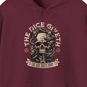 May include: A maroon hoodie with a graphic print of a skull surrounded by snakes and the text "The Dice Giveth The Dice Taketh Away".