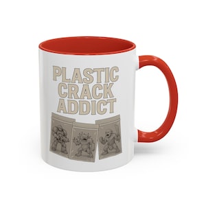 May include: White ceramic mug with a red interior and handle. The mug features the text "PLASTIC CRACK ADDICT" in a beige font, along with illustrations of three cartoon figures in plastic bags. The mug is designed for beverages.