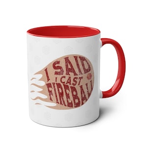 May include: White ceramic mug with a red rim and handle. The mug features a brown and red graphic with the text "I said I cast Fireball".