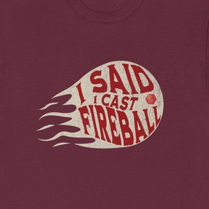 May include: Burgundy t-shirt with a white graphic of a fireball with the text "I said I cast fireball" in red.