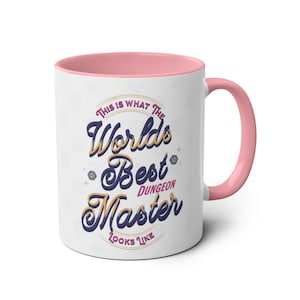 Op de afbeelding: Witte keramische mok met een roze rand en handvat. De mok heeft een afbeelding met de tekst "Dit is hoe de beste dungeon master ter wereld eruitziet".