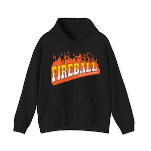Op de afbeelding: Zwarte hoodie met een voorzak en trekkoord. De hoodie heeft het woord "FIREBALL" in witte en gele blokletters, omrand met oranje, met vlammen erboven. De tekst "THE ONLY SOLUTION" staat eronder.