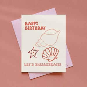 May include: A cream-colored greeting card featuring the red text HAPPY BIRTHDAY and LET'S SHELLEBRATE! along with line art illustrations of a conch shell, a starfish, and a scallop shell, all resting on a light purple envelope.
