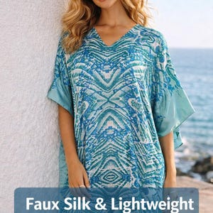 Könnte beinhalten: Blau-weiß gemusterte Tunika aus Kunstseide mit V-Ausschnitt und kurzen Ärmeln. Die Tunika hat ein geometrisches Design und ist leicht. Der Text auf dem Bild lautet "Faux Silk & Lightweight".