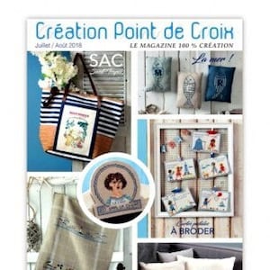 Peut inclure: Une couverture de magazine présentant des motifs de point de croix pour un sac cabas, des coussins, une serviette et de petites pochettes. Le magazine s'intitule "Création Point de Croix" et la couverture présente un thème nautique avec des images de bateaux, d'ancres et de coquillages.