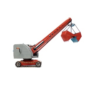 May include: A red toy crane with a gray cab and a metal claw. The crane is on a white background.