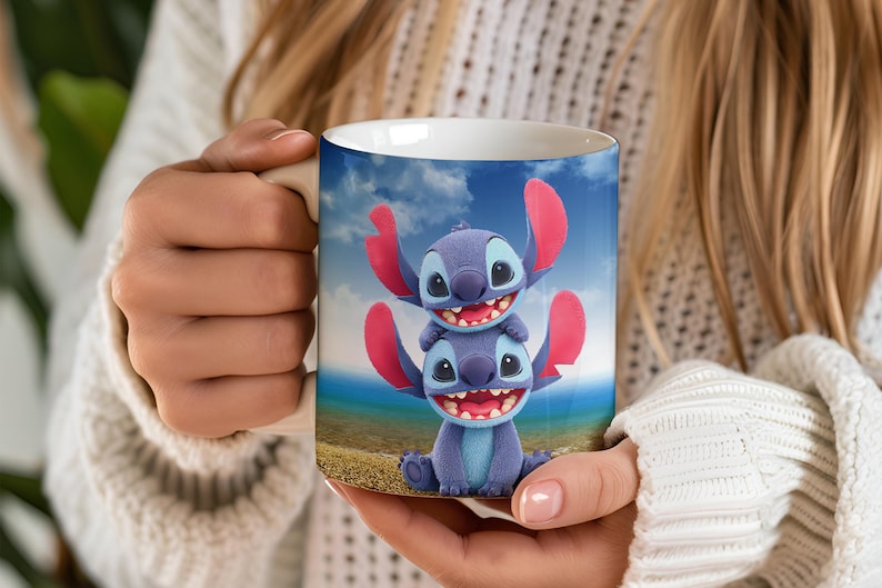Puede incluir: Taza de cer&aacute;mica blanca con un dise&ntilde;o de personaje de dibujos animados en azul y rosa. El dise&ntilde;o muestra dos personajes apilados con orejas grandes y caras sonrientes sobre un fondo de cielo azul y playa. La taza es sostenida por una persona.