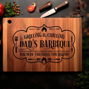 May include: A wooden cutting board with the text "Grilling & Chilling Dad's Barbeque! The Man, The Grill, The Legend" engraved on it.