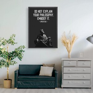 Puede incluir: Impresi&oacute;n enmarcada en blanco y negro con una cita de Epicteto: "No expliques tu filosof&iacute;a. Enc&aacute;rnala." La cita est&aacute; centrada en un fondo negro con una estatua blanca de un hombre sentado en una silla en el fondo.