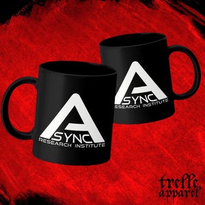 May include: Two black ceramic mugs featuring a white graphic logo of a large letter A with the text ASYNC RESEARCH INSTITUTE printed underneath. The mugs have a standard cylindrical shape with a curved handle on the side for holding the beverage.