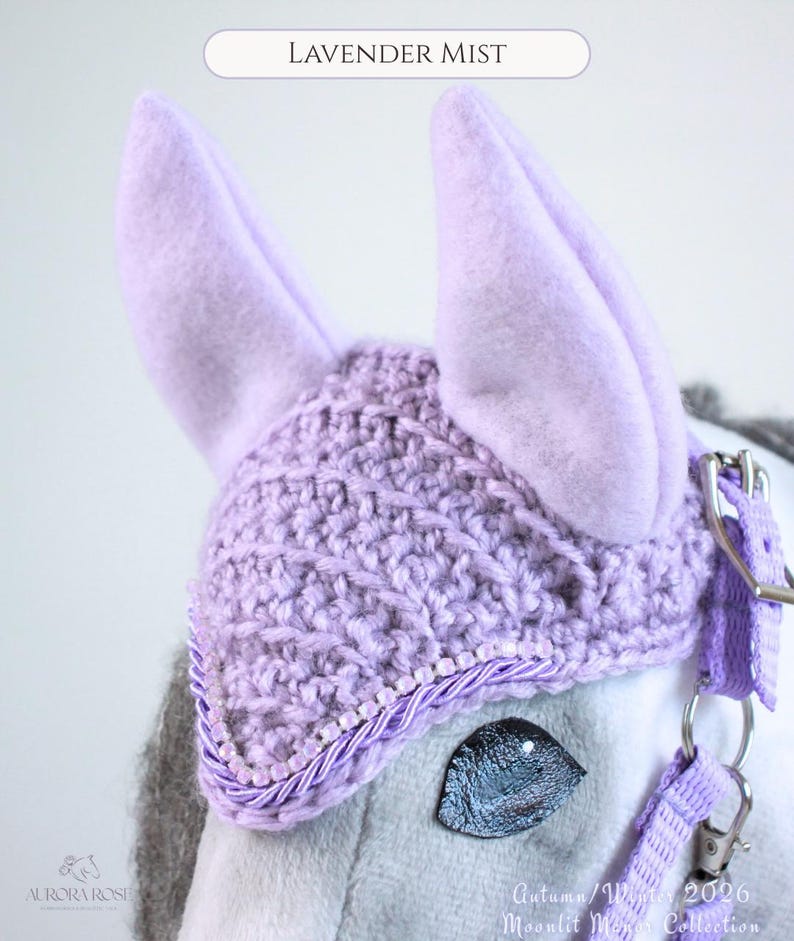 May include: A lavender crochet horse ear bonnet featuring two upright felt ears, a textured knit pattern, and a decorative trim of small beads and twisted cord. The text Lavender Mist, Aurora Rose, and Autumn/Winter 2026 Moonlit Manor Collection appear.
