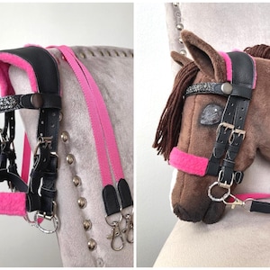 May include: A black bridle with bright pink fleece padding and a browband featuring dark gray crystals. The bridle includes adjustable metal buckles, silver-toned hardware, and long pink reins with black leather ends and metal swivel snap hooks.