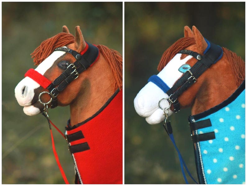 May include: A model horse head featuring a brown coat, white blaze, and yarn mane. It wears a black bridle with a red noseband and a red blanket, or a black bridle with a blue noseband and a light blue blanket with white polka dots.