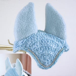 May include: A light blue horse ear bonnet featuring a textured crochet front panel, two soft fleece ear covers, and a decorative trim consisting of a silver rhinestone chain bordered by twisted light blue cord. The text reads Winter Frost.