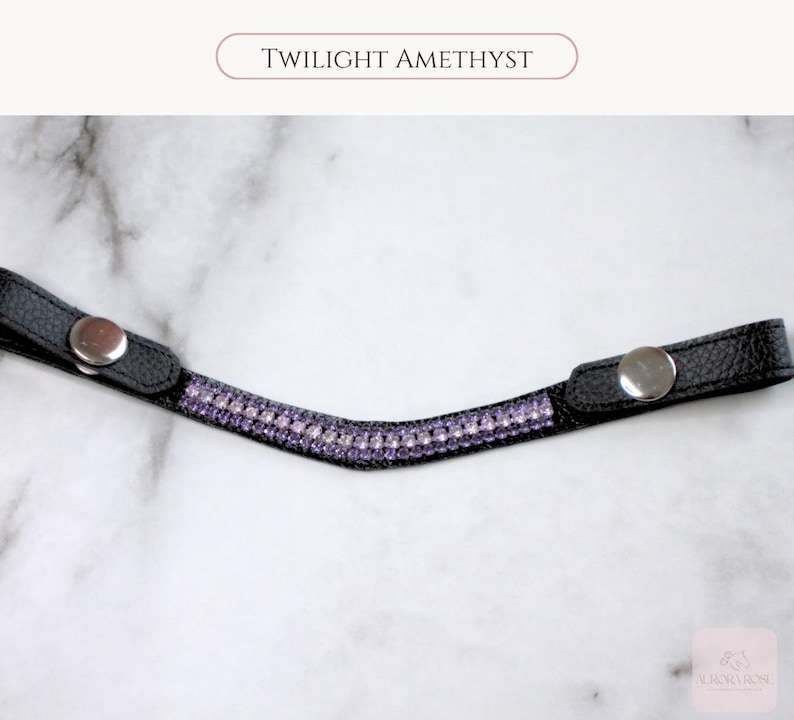 May include: Black leather browband with a row of purple rhinestones. The browband has silver snap closures on each end. The text "TWILIGHT AMETHYST" is printed at the top of the image.