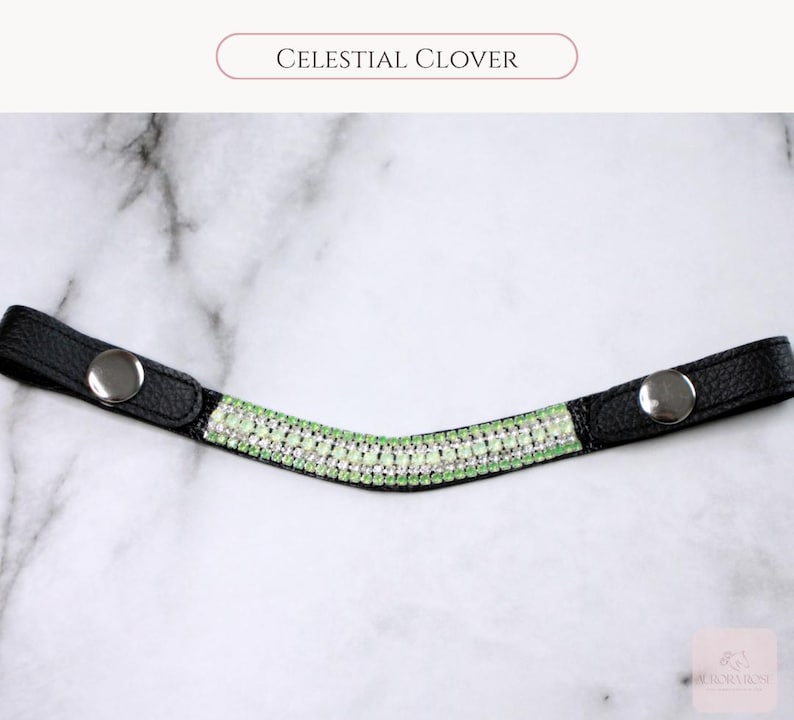 May include: Black leather browband with a curved design, adorned with rows of sparkling light green and clear crystals. The browband has silver snap closures on each end. The text "CELESTIAL CLOVER" is displayed above the browband.