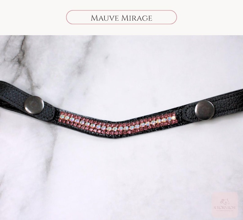 May include: A black leather browband with a row of pink and clear crystals. The browband has silver snap closures on each end. The text "MAUVE MIRAGE" is above the browband.