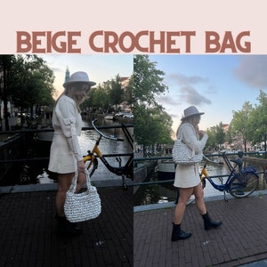 Op de afbeelding: Een vrouw in een witte rok en trui met een witte gehaakte tas en een witte hoed. Ze staat op een brug over een kanaal met een gele fiets op de achtergrond.