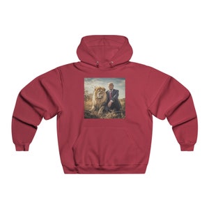 May include: A red hooded sweatshirt with a graphic print of a man sitting next to a lion. The man is wearing a suit and tie. The lion is looking at the camera.