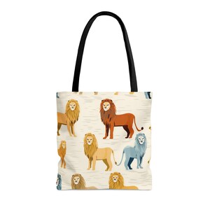 Peut inclure: Un sac fourre-tout beige avec des anses noires présente un motif répété de lions colorés. Les lions sont dans différentes poses et couleurs, notamment orange, jaune, bleu et marron.