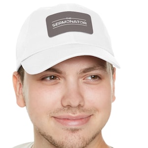 Peut inclure: Casquette de baseball blanche avec un patch gris sur lequel est inscrit "THE SERMONATOR" en lettres blanches.