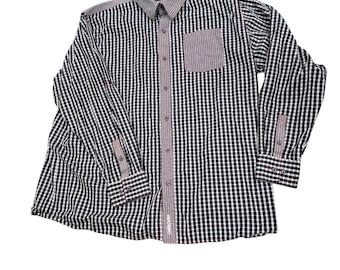 May include: A long-sleeved button-down shirt with a black and white checkered pattern. The shirt features a pocket and trim in a contrasting burgundy color. The collar and cuffs have a subtle pattern. The shirt is laid flat on a white surface.