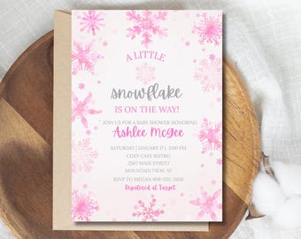 Op de afbeelding: Een uitnodiging voor een babyshower met een sneeuwvlokthema. De uitnodiging bevat roze aquarel sneeuwvlokken en de tekst "A Little Snowflake Is On The Way!" De uitnodiging is voor Ashlee McGee.