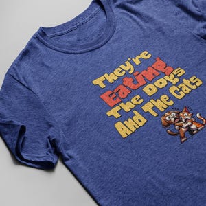 Trump Quote Shirt – “They’re Eating The Dogs And The Cats” Funny Political T-Shirt, Cartoon Dog & Cat, Meme Graphic Tee, Retro Humor Shirt