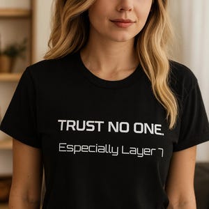 May include: Black t-shirt with the white text "TRUST NO ONE. Especially Layer 7." The shirt is a crew neck style and is paired with blue jeans. The overall look is casual and modern.